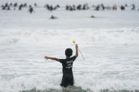 Nathan Rangel, 11, jumps in the water carrying a rose as surfers participate in a paddle out ceremony at "The Ink Well," a beach historically known as a surfing refuge for African Americans, to honor the life of George Floyd on Friday, June 5, 2020, in Santa Monica, Calif. Floyd died after he was restrained in police custody on Memorial Day in Minneapolis. (AP Photo/Ashley Landis)