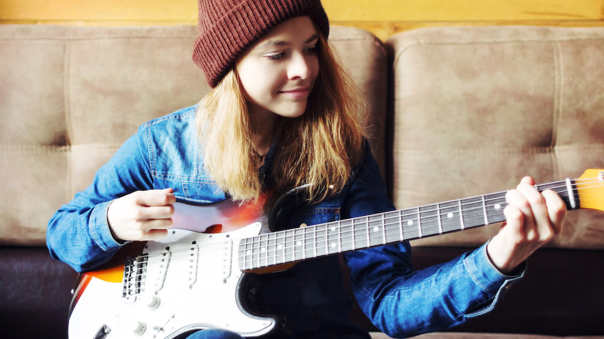  Girl in red beanie playing a Stratocaster. 