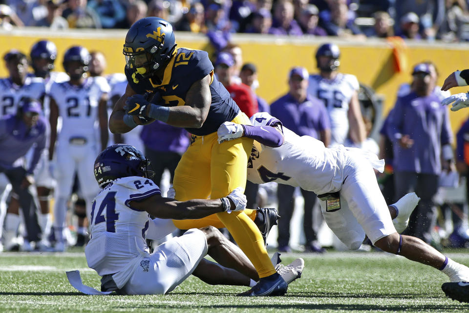 West Virginia tight end CJ Donaldson (12) is tackled TCU cornerback Josh Newton (24) and safety Namdi Obiazor (4) during the first half of an NCAA college football game in Morgantown, W.Va., Saturday, Oct. 29, 2022. (AP Photo/Kathleen Batten)
