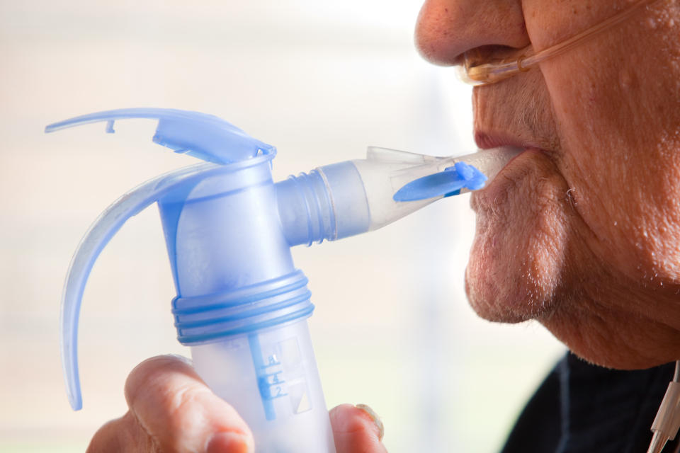 A close up of a 91 year old man using a nebulizer.