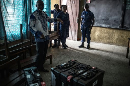 A polling official and Congolese policemen guard voting machines in Kinshasa