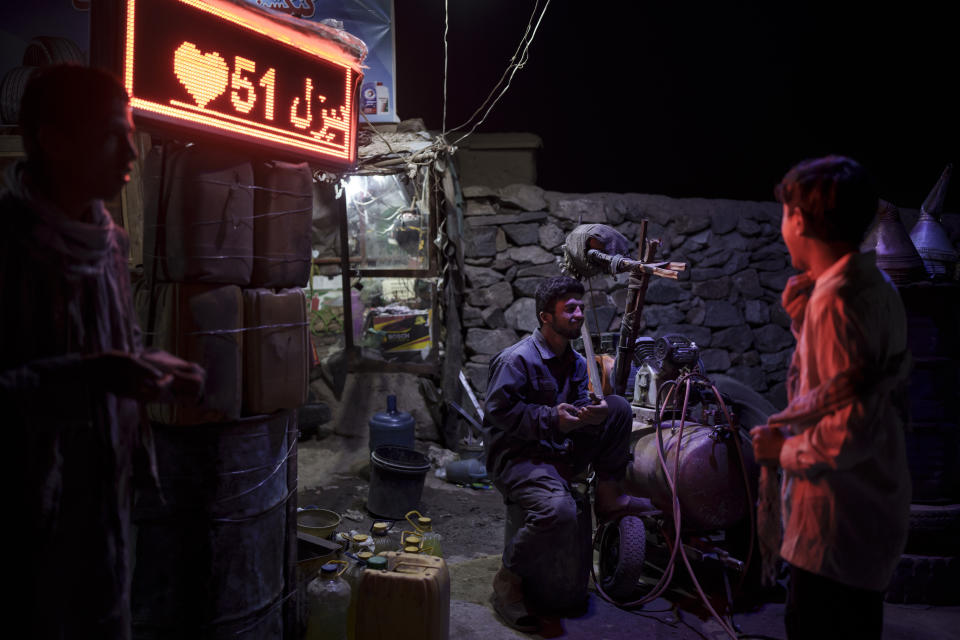 A tire repairman chats with boys as he waits for customers on the side of a road in Kabul, Afghanistan, Tuesday, Sept. 14, 2021. (AP Photo/Felipe Dana)
