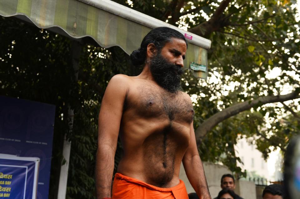 Indian yoga guru, Baba Ramdev demonstrates a yoga exercise to the media during a press conference on the declaration of a ‘yoga day’ in New Delhi in 2014 (AFP via Getty Images)