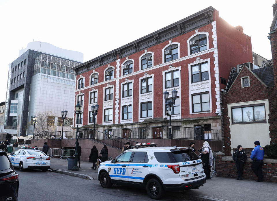 Police cars and officers outside a building, indicating an active investigation at the scene