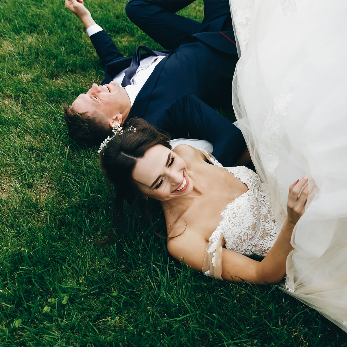 Bride and groom lying in grass and laughing