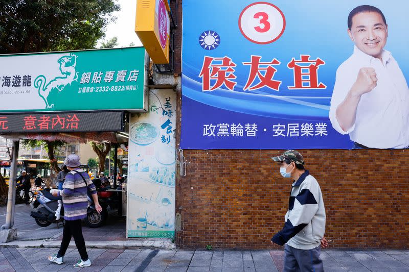 People walk past a campaign ad for Hou Yu-ih, a candidate for Taiwan's presidency, from the main opposition party Kuomintang (KMT)