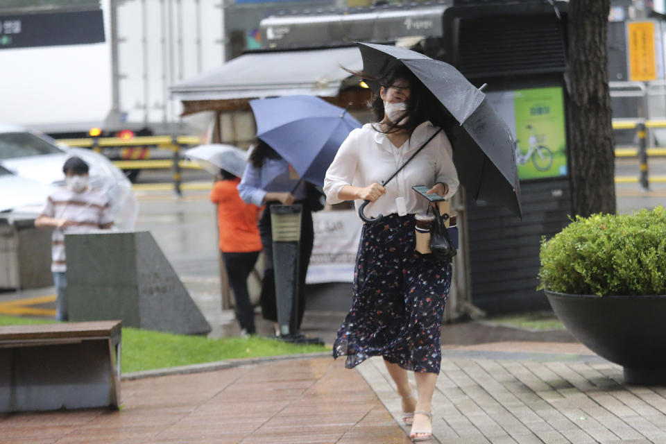 A woman holds an umbrella against the strong wind and rain caused by Typhoon Bavi in Seoul, South Korea, Thursday, Aug. 27, 2020. Typhoon Bavi that grazed South Korea and caused some damage has made landfall in North Korea early Thursday. South Korean authorities said there were no immediate reports of casualties, and North Korea has not reported any damages. (AP Photo/Ahn Young-joon)