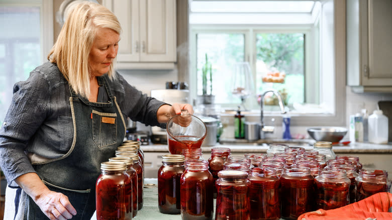 woman filling jars red liquid