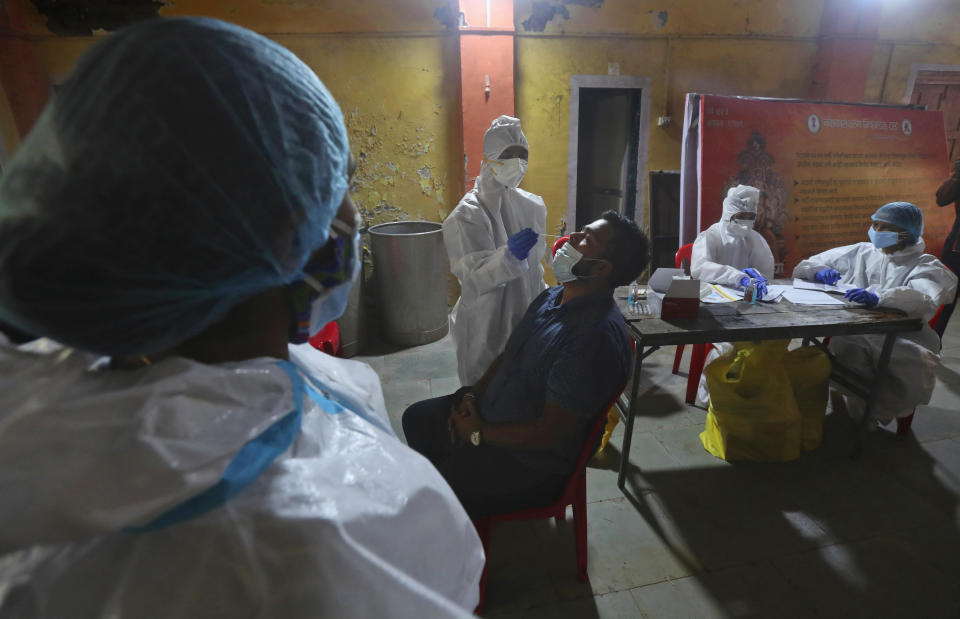 A health worker collects a swab sample to test for COVID-19 in Mumbai, India, Wednesday, Sept. 16, 2020. India's total of coronavirus infections passed 5 million Wednesday, still soaring and testing the feeble health care system in tens of thousands of impoverished towns and villages. (AP Photo/Rafiq Maqbool)