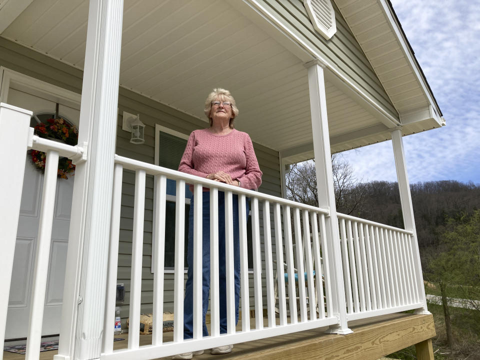 Deborah Hansford stands on the porch of her new home in Jackson, Ky, Wednesday, March 29, 2023. Hansford's home was destroyed in the 2022 flooding. A nonprofit group built a home for her on a new street on higher ground safe from future flooding, and she moved in late March. (AP Photo/Dylan Lovan)