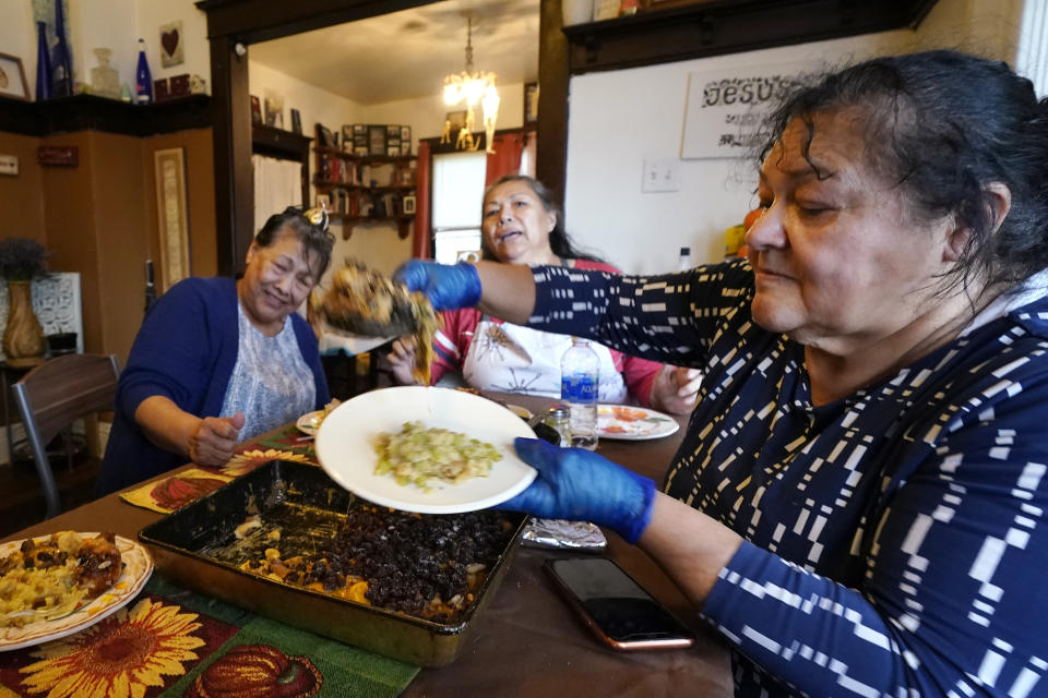 Olga Garcia, right, prepares a plate of food for her sisters Francis Garcia, left, and Anna Garcia at an afternoon family meal Wednesday, Nov. 4, 2020, in the family home in Sedro-Woolley, Wash. On any other Thanksgiving, dozens of Olga's family members would squeeze into her home for the holiday. But this year, she'll deliver food to family spread along 30 miles of the North Cascades Highway in Washington state. If the plan works, everyone will sit down to eat in their own homes at precisely 6:30 p.m. and join a group phone call. (AP Photo/Elaine Thompson)