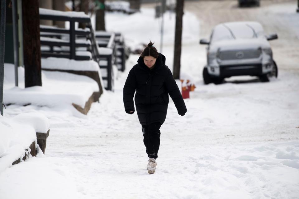 Parker Graye walks over a snow-covered sidewalk after seeing what the road conditions were like in Nashville, Tenn., Tuesday, Jan. 16, 2024.