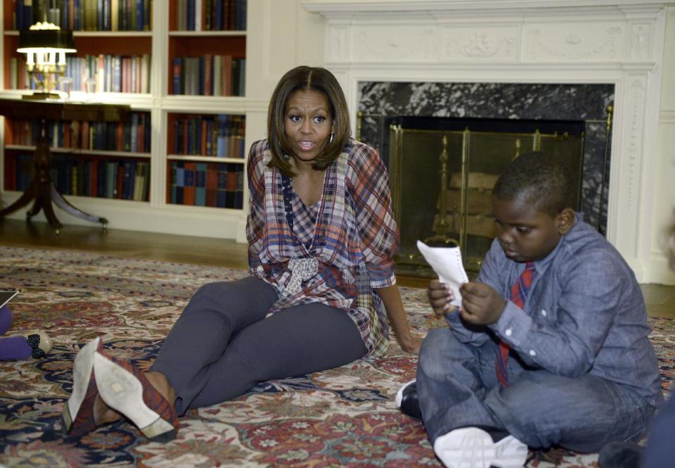 First lady Michelle Obama sits on the floor with "kid reporter" Justin Creppy, 6, from Upper Marlboro, Md., Monday, April 21, 2014, in the Library of the White House in Washington. (AP Photo/Susan Walsh)