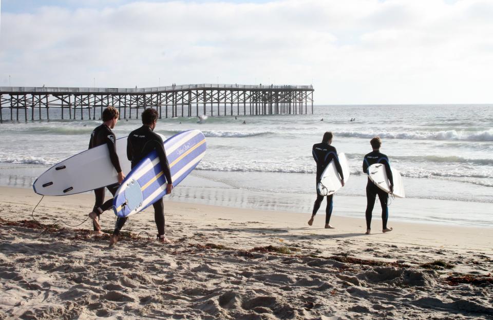Surfers set out in search of waves in San Diego.