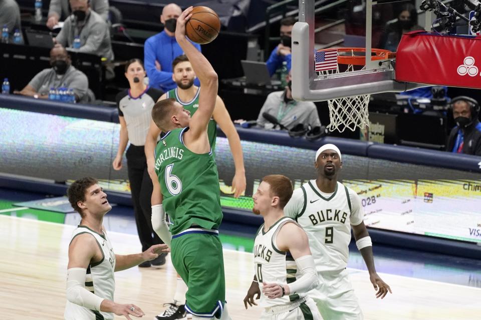 Milwaukee Bucks' Brook Lopez (11), Donte DiVincenzo (0) and Bobby Portis (9) defends as Dallas Mavericks center Kristaps Porzingis (6) goes up for a dunk in the second half of an NBA basketball game in Dallas, Thursday, April 8, 2021. (AP Photo/Tony Gutierrez)