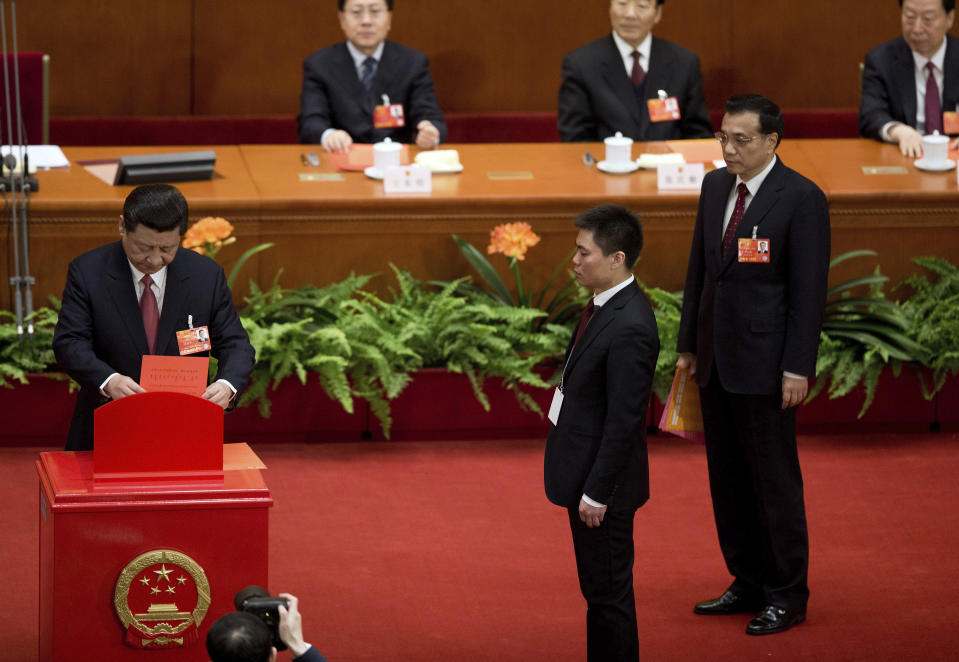 FILE - Incoming Chinese President Xi Jinping, left, casts his vote into a box as Vice Premier Li Keqiang, right, looks on during a plenary session of the National People's Congress held at the Great Hall of the People in Beijing on March 14, 2013. Chinese President Xi Jinping was the son of a communist revolutionary leader, a victim of the Cultural Revolution and a provincial leader who promoted economic growth before ascending to the very top a decade ago. (AP Photo/Andy Wong, File)