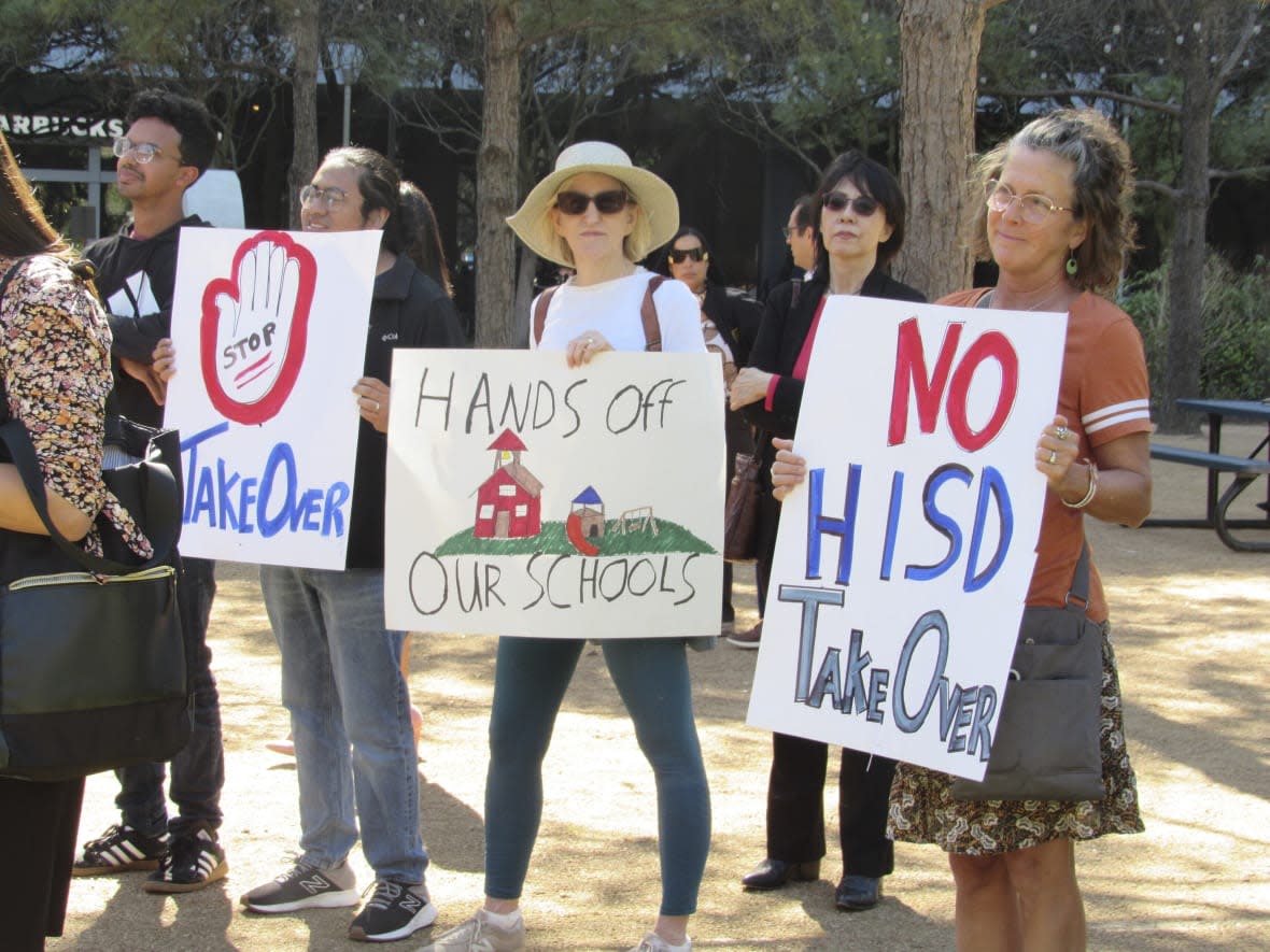 FILE – People hold up signs at a news conference, Friday, March 3, 2023, in Houston while protesting the proposed takeover of the city’s school district by the Texas Education Agency. Texas officials on Wednesday, March 15, announced a state takeover of Houston’s nearly 200,000-student public school district, the eighth-largest in the country, acting on years of threats and angering Democrats who assailed the move as political. (AP Photo/Juan A. Lozano)