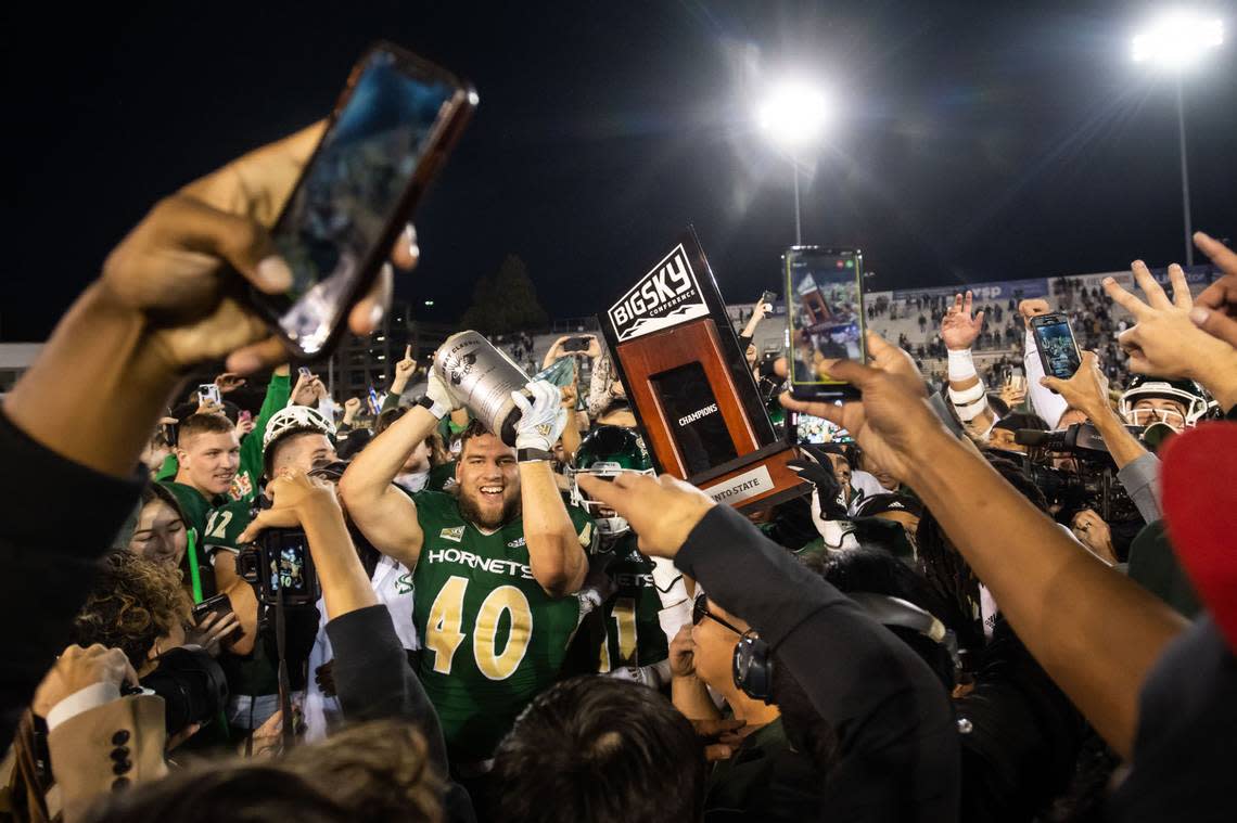 Sacramento State Hornets defensive lineman Killian Rosko (40), left, raises the Causeway Classic prize alongside a conference trophy while players, students and fans rush the field after their win over UC Davis in 2022. Xavier Mascareñas/Sacramento Bee file