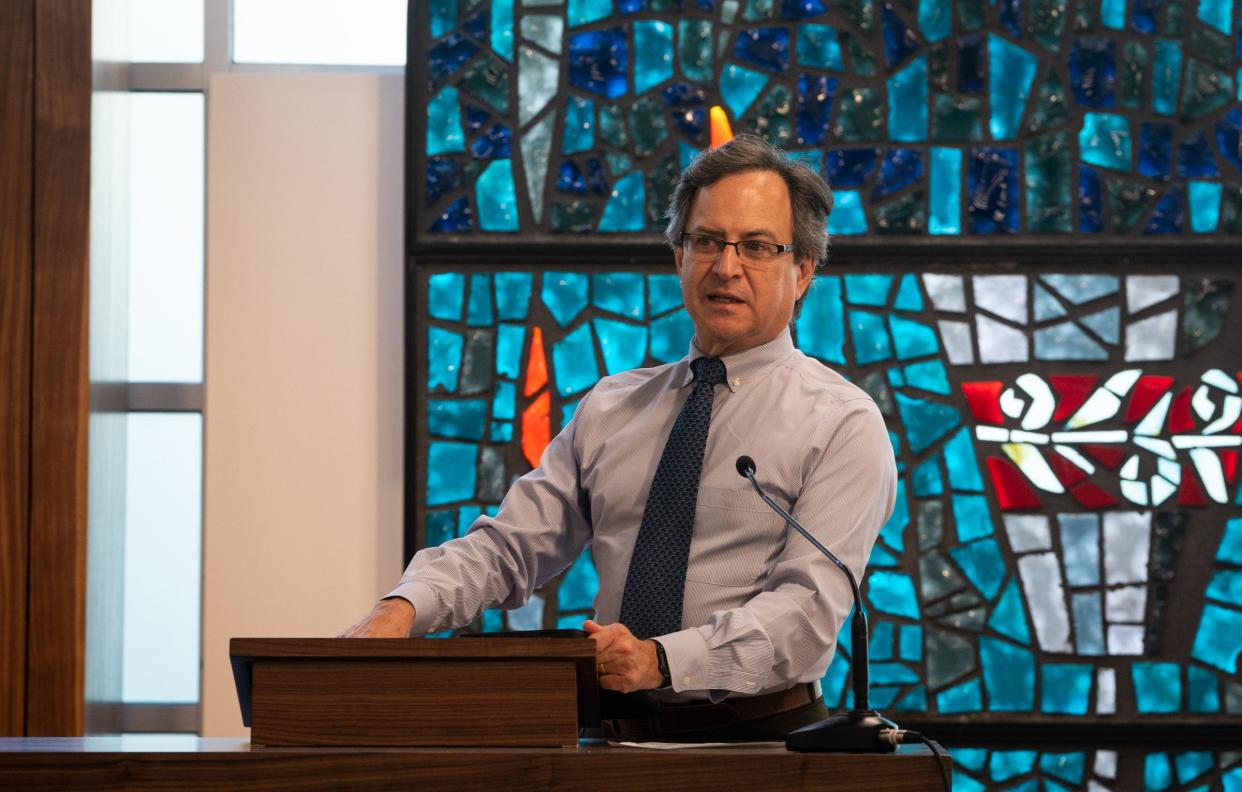 Rabbi Steven Folberg chats with some congregation members as Congregation Beth Israel. Behind him is one of the stained glass window that was saved after the arson on Oct. 31, 2021.