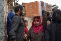 A woman carries a carton filled with food distributed by the non-governmental organization Resala Nour Ala Nour to people who have been highly affected by the coronavirus outbreak, in Cairo, Egypt, Thursday, April 9, 2020. (AP Photo/Nariman El-Mofty)