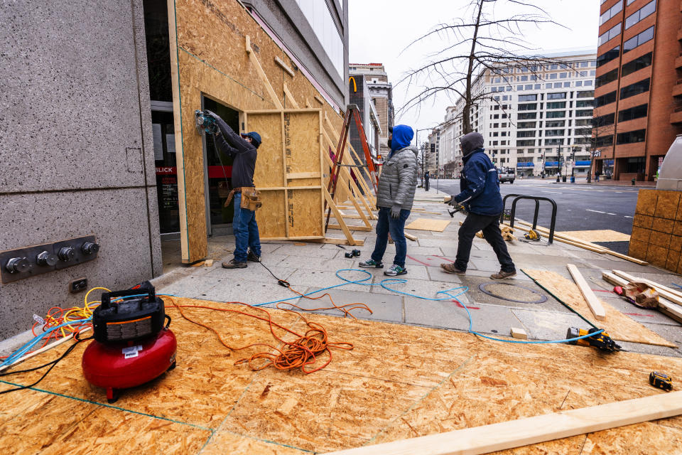 Workers board up the glass panel windows at a downtown Washington store, Tuesday, Jan. 5, 2021, in Washington. (AP Photo/Manuel Balce Ceneta)