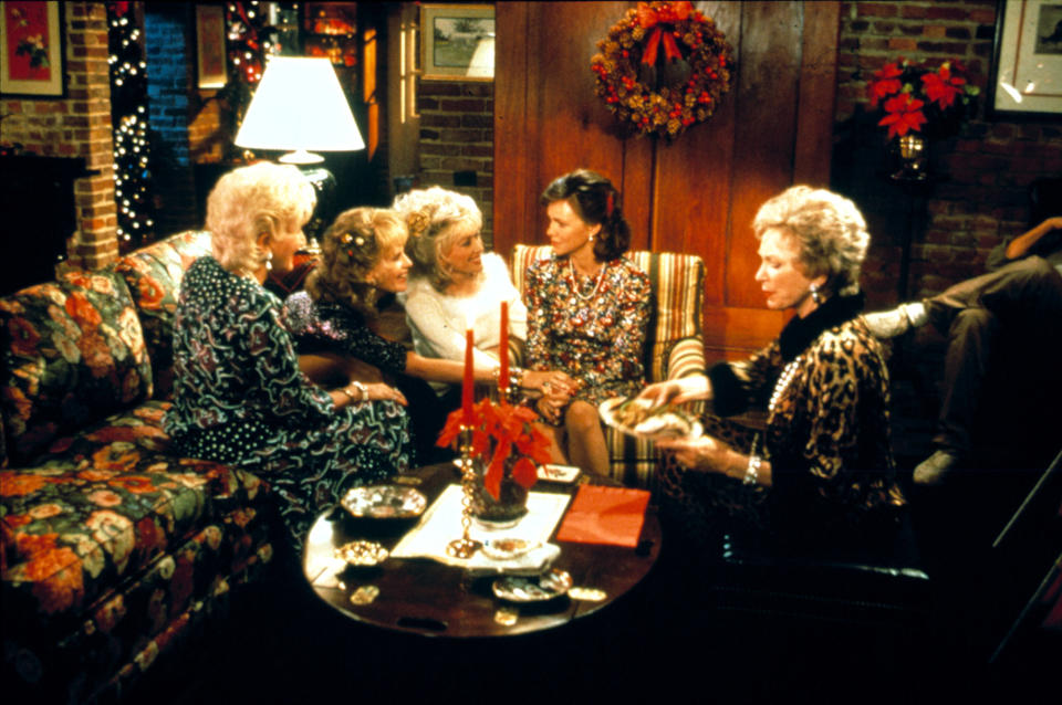 Four women sit and talk together on the couch