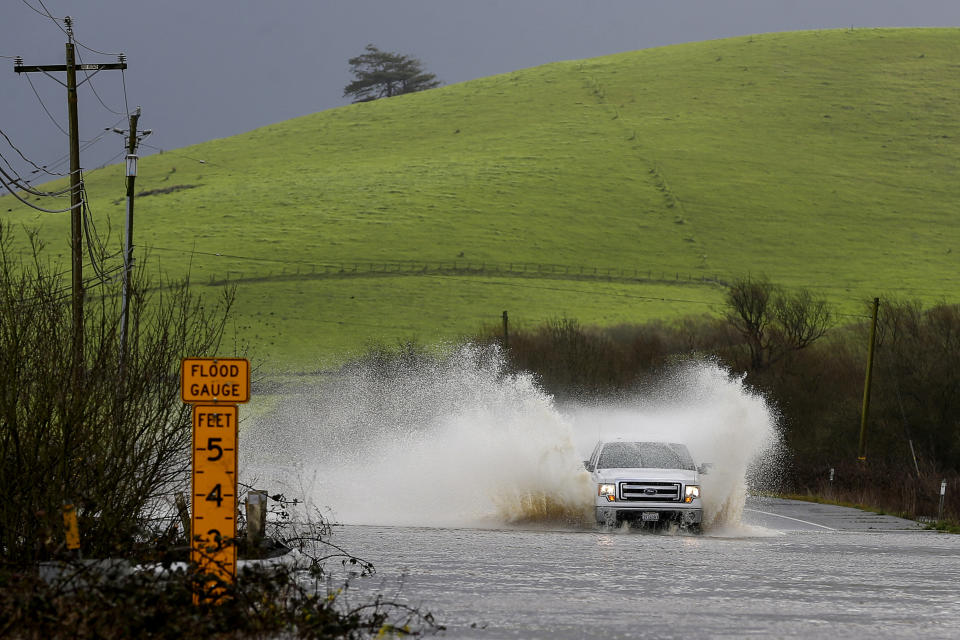 FILE - A truck drives through a flooded Valley Ford Road on Feb. 19, 2024, in Bloomfield, Calif. California's current rainy season got off to a slow start but has rebounded with recent storms that have covered mountains in snow and unleashed downpours, flooding and mudslides. The water content of the vital Sierra Nevada snowpack has topped 80% of normal to date while downtown Los Angeles has already received more than an entire year's average annual rainfall. (Christopher Chung/The Press Democrat via AP, File)