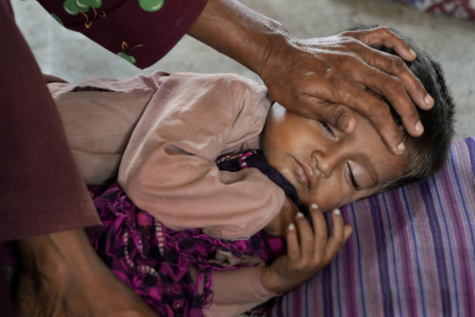 A woman takes care of her child as she with other families take shelter in a school after fleeing from their villages of costal areas due to Cyclone Biparjoy approaching, in Gharo near Thatta, a Pakistan's southern district in the Sindh province, Wednesday, June 14, 2023. In Pakistan, despite strong winds and rain, authorities said people from vulnerable areas have been moved to safer places in southern Pakistan's districts. With Cyclone Biparjoy expected to make landfall Thursday evening, coastal regions of India and Pakistan are on high alert. (AP Photo/Fareed Khan)