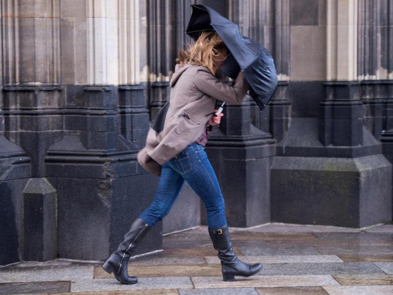 Eine junge Frau kämpft in Köln mit ihrem Regenschirm. Foto: Marius Becker