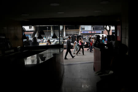 People walk in front of a restaurant during a blackout in Caracas, Venezuela March 7, 2019. REUTERS/Carlos Jasso