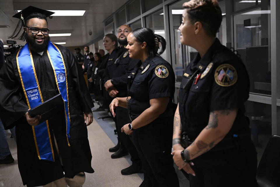 Graduate Alpha Jalloh walks with his diploma past correction officers congratulating him at the first-ever college graduation ceremony at MacDougall-Walker Correctional Institution, Friday, June 9, 2023, in Suffield, Conn. The ceremony was held under a partnership established in 2021 by the University of New Haven and the Yale Prison Education Initiative. (AP Photo/Jessica Hill)