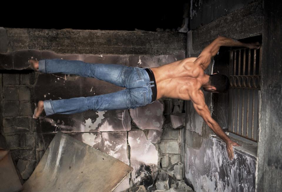 Palestinian Eyad Ayad, of team Bar Palestine, suspends during street exercises amid the destruction in Gaza City on August 3, 2015. Street workout, that is still new to Gaza, is a growing sport across the world with annual competitions and events.