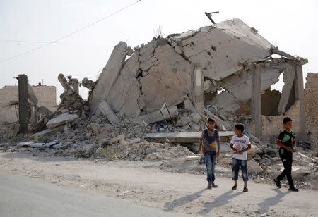 Boys walk past damaged buildings in Bizaah, northeast of Aleppo's countryside, Syria September 16, 2017. Picture taken September 16, 2017. REUTERS/Khalil Ashawi