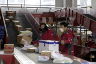 In this Tuesday, Feb. 18, 2020, photo, delivery workers for Chinese e-commerce giant JD.com sort out parcels at a distribution center in Beijing, China. JD and rivals including Pinduoduo, Miss Fresh and Alibaba Group's Hema are scrambling to fill a boom in orders while protecting their employees. E-commerce is one of the few industries to thrive after anti-virus controls starting in late January closed factories, restaurants, cinemas, offices and shops nationwide and extinguished auto and real estate sales. (AP Photo/Ng Han Guan)