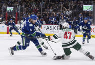 Vancouver Canucks' Brock Boeser (6) takes a shot on goal as Minnesota Wild's Alex Goligoski (47) defends during the second period of an NHL hockey game, Tuesday, Oct. 26, 2021 in Vancouver, British Columbia. (Darryl Dyck/The Canadian Press via AP)