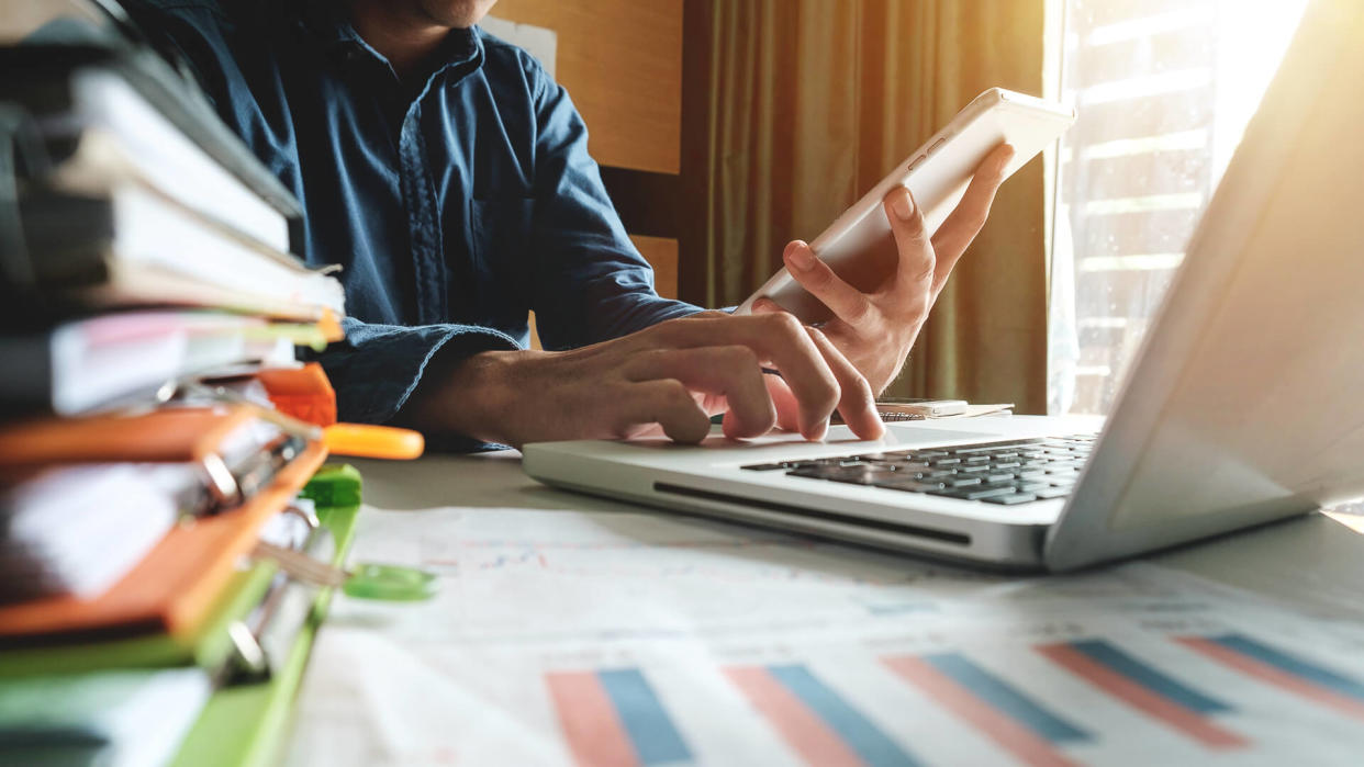 guy inputing financial record data into computer from tablet