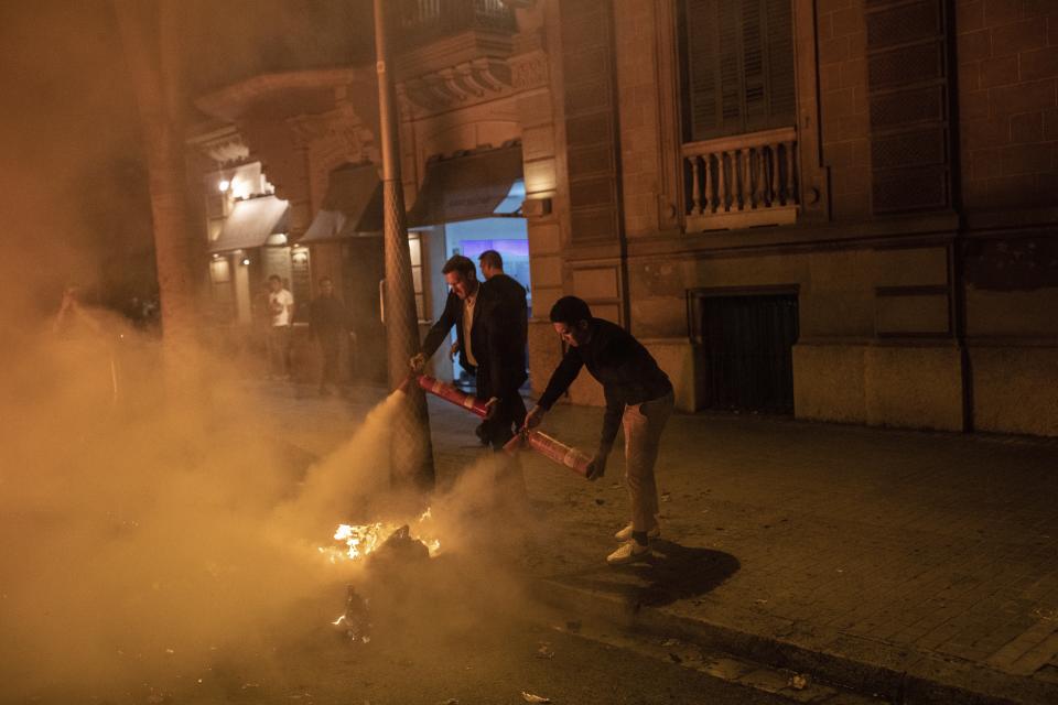 Varios peatones usan extintores para apagar las barricadas independentistas (AP Photo/Bernat Armangue)