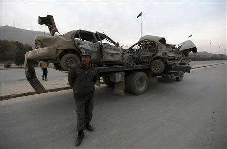 A policeman stands in front of a truck carrying two vehicles destroyed in a suicide attack in Kabul, November 16, 2013. REUTERS/Mohammad Ismail