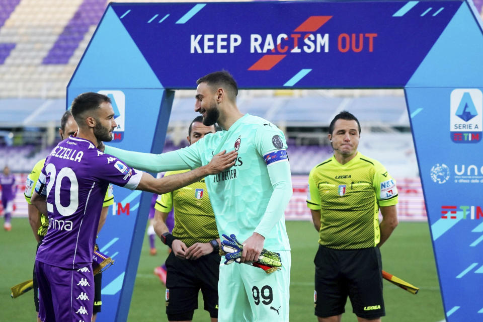 AC Milan's goalkeeper Gianluigi Donnarumma, center, and Fiorentina's German Pezzella, left, greet each other under a banner reading "Keep racism out" as part of the new anti-racism campaign launched last Sunday by the Italian soccer League, prior to a Serie A match between Fiorentina and AC Milan at the Artemio Franchi stadium in Florence, Italy, Sunday, March 21, 2021. Serie A’s efforts to combat racism inside its stadiums was in shambles little more than a year ago when league CEO Luigi De Siervo decided to take matters into his own hands. (Spada/LaPresse via AP)