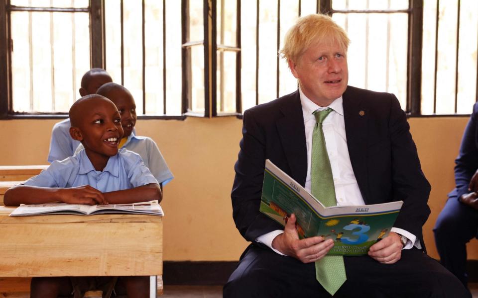 Boris Johnson looks on as school children take part in a lesson during a visit to The GS Kacyiru II School in Kigali - Dan Kitwood/AFP