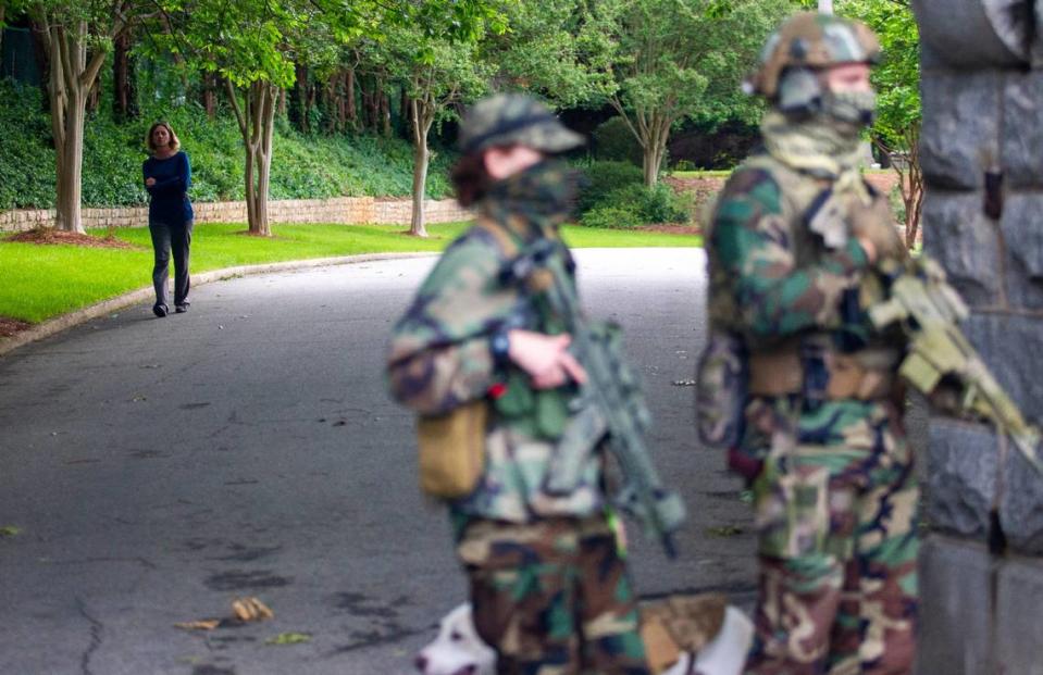 A woman walks through Oakwood Cemetery as a group of about nine mostly-armed demonstrators gathered to exercise their 2nd Amendment rights in front of the main gateway at the cemetery in Raleigh Friday, May 1, 2020.