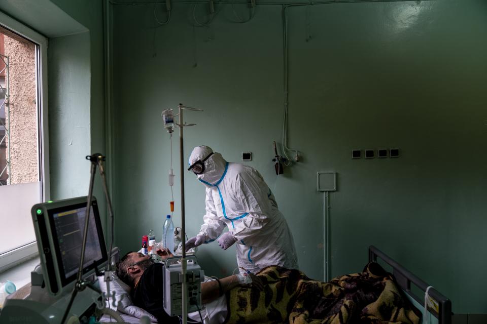In this photo taken on Monday, May 4,2020, doctor Kosyantyn Dronyk, wearing a special suit to protect against coronavirus, helps a patient with his oxygen mask at an intensive care unit at a regional hospital in Chernivtsi, Ukraine. Ukraine's troubled health care system has been overwhelmed by COVID-19, even though it has reported a relatively low number of cases. (AP Photo/Evgeniy Maloletka)