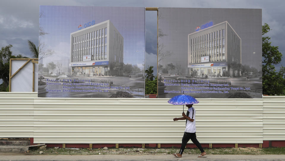 In this Wednesday, April 10, 2019, photo, a man walks past a development site for a Chinese Investment bank in Nuku'alofa, Tonga. China is pouring billions of dollars in aid and low-interest loans into the South Pacific, and even in the far-flung kingdom of Tonga there are signs that a battle for power and influence among much larger nations is heating up and could exact a toll. (AP Photo/Mark Baker)