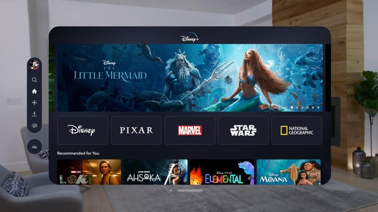 Image of the Disney+ app for VisionOS. A floating window shows the service's home menu in a living room.