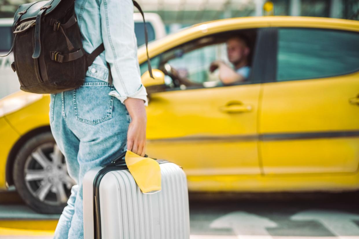 A young woman with a suitcase waiting for a taxi at an aiport