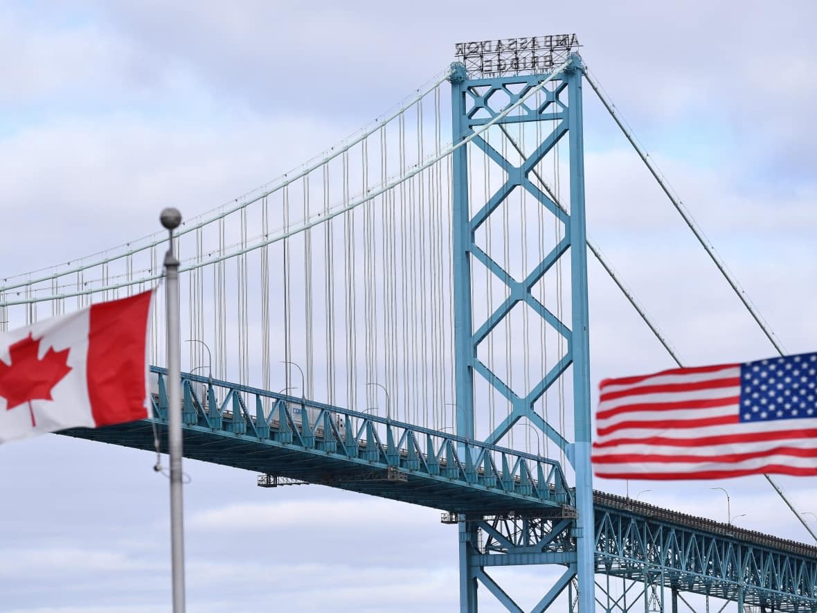 Canadian and American flags fly near the Ambassador Bridge at the Canada-U.S. border crossing in Windsor, Ont. on Saturday, March 21, 2020, the first day the border was closed to non-essential travel due to COVID-19. (Rod Gurdebeke/The Canadian Press - image credit)