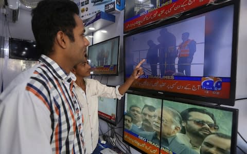 People watch television news showing the departure of Pakistan's ailing former Prime Minister Nawaz Sharif in Karachi, Pakistan, Tuesday, Nov. 19, 2019.  - Credit: AP