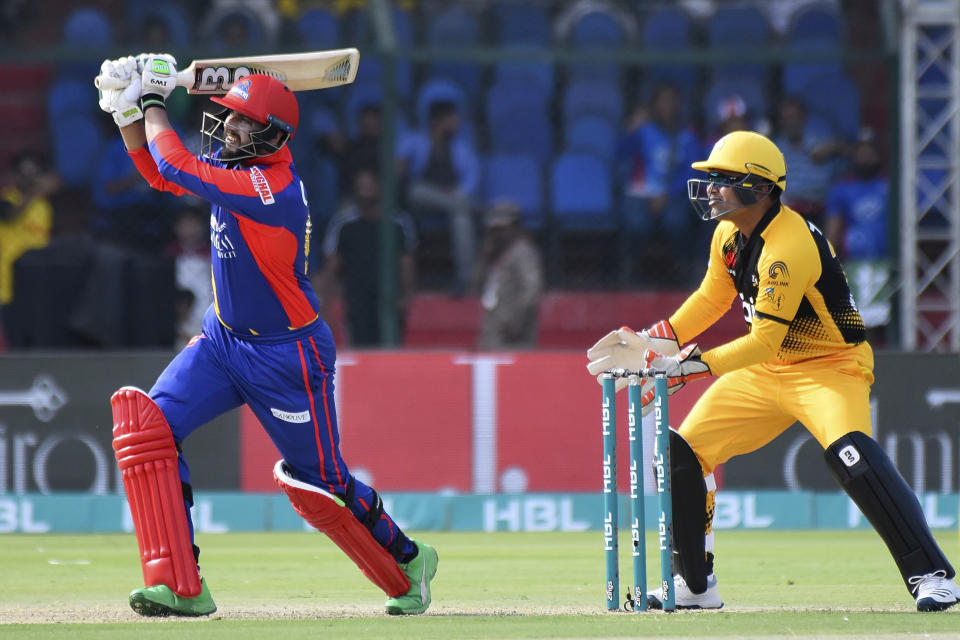 Karachi Kings captain Imad Wasim hits a six during his half century against Peshawar Zalmi in the Pakistan Super League match at the National Stadium in Karachi, Pakistan, Friday, Feb. 21, 2020. Wicket keeper Kamran Akmal is seen on right. (AP Photo/Fareed Khan)