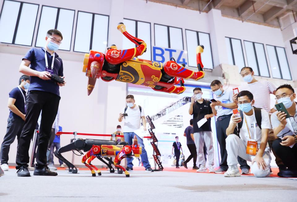 BEIJING, CHINA - SEPTEMBER 10: Visitors watch as a robot dog performs a backward somersault at the booth of Unitree Robotics during 2021 World Robot Conference (WRC) at Beijing Etrong International Exhibition & Convention Center on September 10, 2021 in Beijing, China. (Photo by Fu Ding/Beijing Youth Daily/VCG via Getty Images)