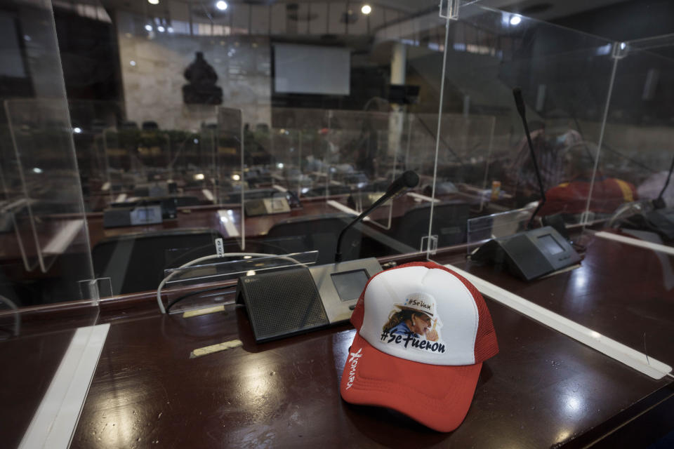 A baseball cap with an image of President-elect Xiomara Castro that carries the Spanish hashtags: They're going. They're gone." sits on a lawmaker's desk inside Congress, which Castro's supporters are occupying in Tegucigalpa, Honduras, Wednesday, Jan. 26, 2022. The new president's supporters say they want to block opposition attempts to take over leadership of Congress, which could threaten her ability to govern after she is sworn in Jan. 27. (AP Photo/Moises Castillo)